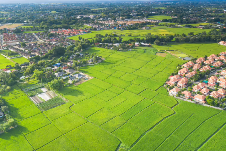 Vista aérea de un terreno dividido en parcelas junto a una urbanización de casas